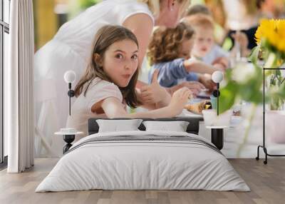 Small children sitting at the table outdoors on garden party in summer, eating. Wall mural