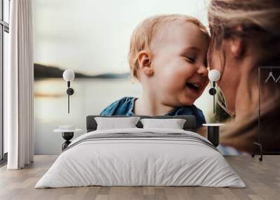 Smiling mother holding toddler outdoors Wall mural