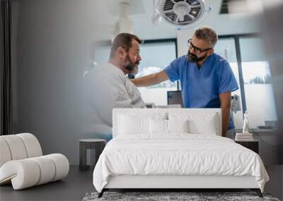 Supportive doctor soothing a worried overweight patient, discussing test result in emergency room. Illnesses and diseases in middle-aged men's health. Compassionate physician supporting stressed Wall mural