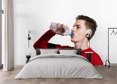 Teenage boy with smartphone and earphones, drinking water. Isola Wall mural