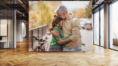 Teenage daughter hugging her father outside in town when spending time together. Wall mural