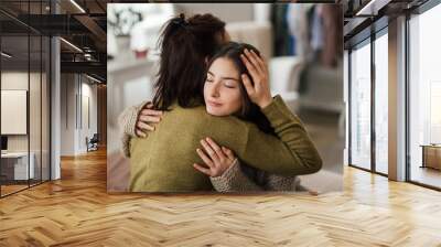 Teenage girl hugging her mother at home. Wall mural