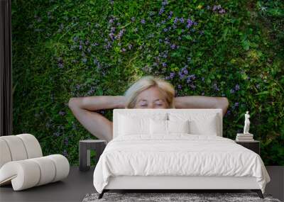 Top view of relaxed senior woman lying down in field of wild thymus flowers, herbal medicine concept. Wall mural