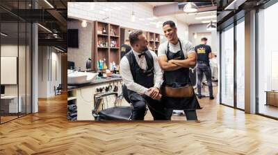 Two male haidressers and hairstylists sitting in barber shop. Wall mural