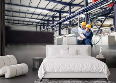 Two project managers standing in modern industrial factory. Manufacturing facility with robotics, robotic arms and automation. Storing products and materials in warehouse. Wall mural