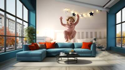 Two small children jumping on bed indoors at home, having fun. Wall mural