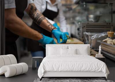 Unrecognizable chef with gloves cutting vegetables indoors in restaurant kitchen. Wall mural