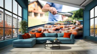 Unrecognizable man cooking seafood on a barbecue grill in the backyard. Wall mural