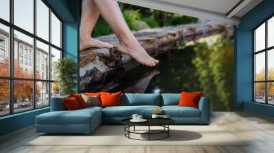 Unrecognizable young woman is dipping her foot in cool water of pond, refreshing and hardening concept. Wall mural