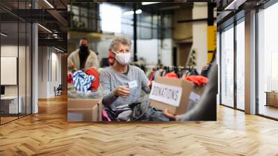 Volunteers sorting out donated clothes in community charity donation center, coronavirus concept. Wall mural