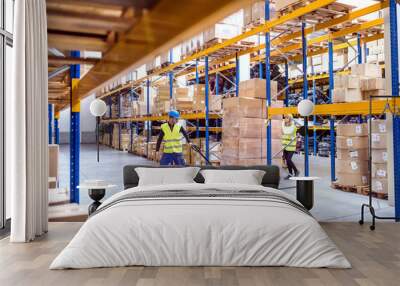 Warehouse workers pulling a pallet truck. Wall mural