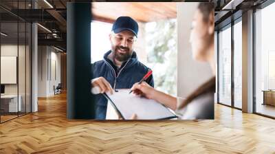 Woman receiving parcel from delivery man at the door. Wall mural