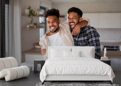 Young adult brothers in kitchen indoors at home, having fun. Wall mural