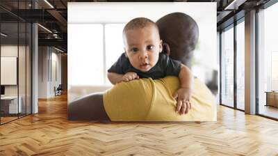 Young afro-american father holding his baby son in the arms Wall mural