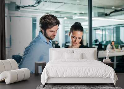 Young businesspeople with tablet in an office, working. Wall mural