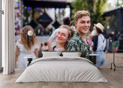 Young couple at summer festival, standing back to back. Wall mural