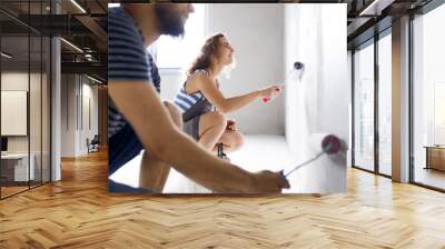 Young couple painting walls in their new house. Wall mural