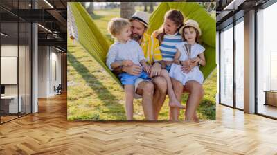 Young family with little kids enjoying their holiday in exotic country, lying in hammock. Wall mural