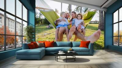 Young family with little kids enjoying their holiday in exotic country, lying in hammock. Wall mural