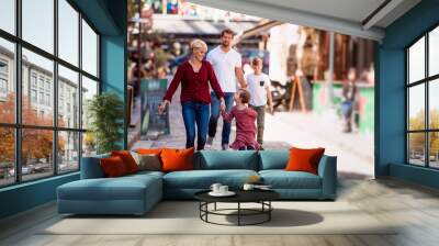 young family with two small children walking outdoors in town on holiday. Wall mural