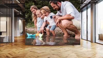 Young family with two toddler children outdoors by the river in summer, playing. Wall mural