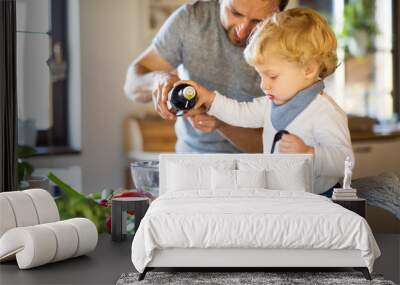 Young father with a toddler boy cooking. Wall mural