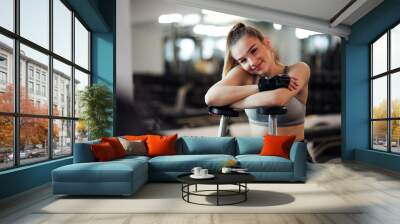 Young girl or woman with dumbbells, doing workout in a gym. Wall mural