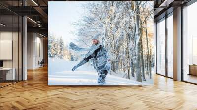 Young man having fun in snow outdoors in winter. Wall mural