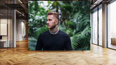 Young man standing in botanical garden. Copy space. Wall mural