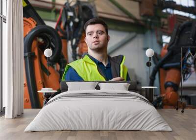 Young man with Down syndrome working in industrial factory, social integration concept. Wall mural