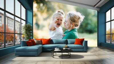 Young mother comforting crying small daughter in summer in nature. Wall mural