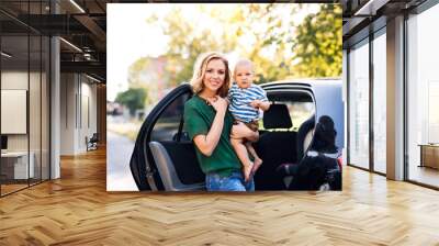 Young mother with her little baby boy standing by the car. Wall mural