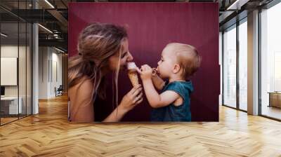 Young mother with small toddler girl outdoors in summer, eating ice cream. Wall mural