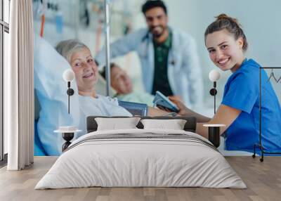 Young nurse chcecking blood presure to senior patient. Wall mural