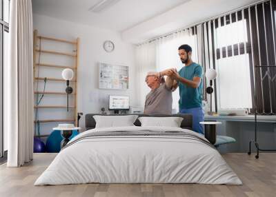 Young physiotherapist exercising with senior patient in a physic room Wall mural