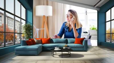 Young woman architect sitting at the desk indoors in home office, working. Wall mural