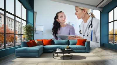 Young woman doctor explaining diagnosis to teenage girl in her ambulance. Wall mural