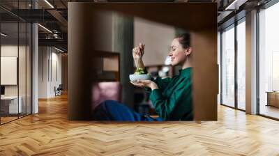 Young woman eating salad in an office. Wall mural