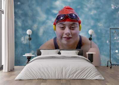 Young woman with Down syndrome swimming in swimming pool and looking at camera Wall mural