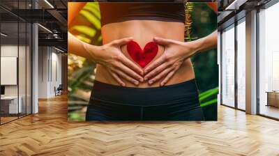 An image of a woman holding a red heart shaped in her stomach with a natural background. Wall mural