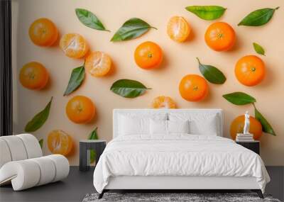 An orange yellow tangerine in a row with green leaves on a beige background, copy space. Mandarin fruits as a food frame with open space, top view, flat lay, minimalist style still life. Wall mural