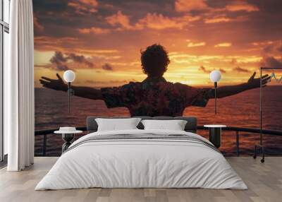 View of a young man on a yacht or cruise ship, wearing a light blue tropical shirt, with the ocean in the background and the sunset behind him. Wall mural