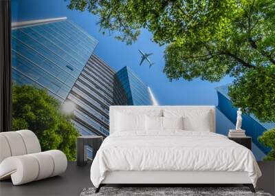 Tall city buildings and a plane flying overhead. Wall mural