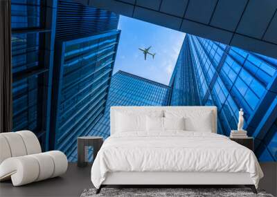 Tall city buildings and a plane flying overhead. Wall mural