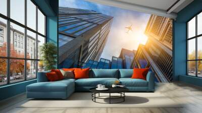 Tall city buildings and a plane flying overhead. Wall mural