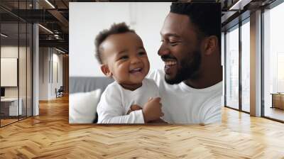 A Black father holding his smiling baby boy in a bedroom. Wall mural