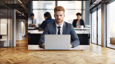 Portrait of a young businessman working on a laptop in a modern office. Wall mural