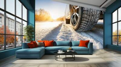 Winter tire with detail of car tires in winter snowy season on the road covered with snow and morning sun light Wall mural