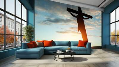 Silhouette of the crucified Jesus Christ on the cross on background of sunset sky. Wall mural