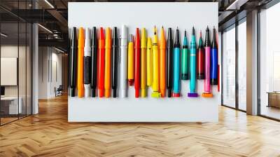 A collection of art markers and pens in various colors isolated against a simple studio backdrop suitable for creative presentations. Wall mural